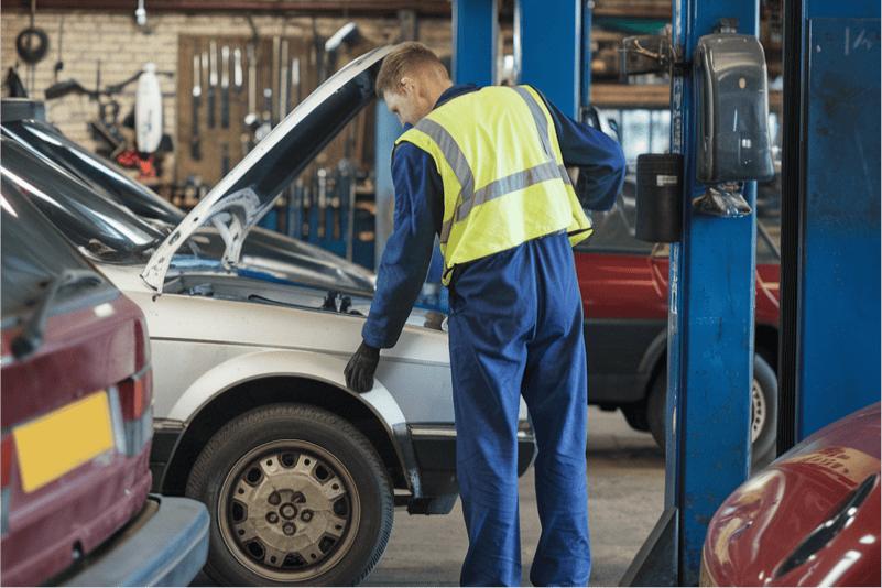 A man fixing a car in a garage.