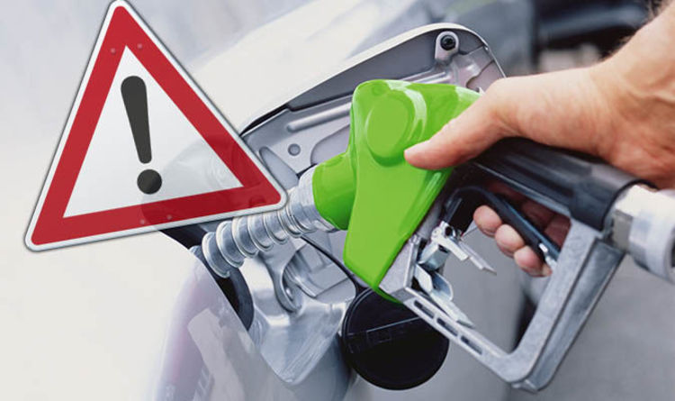 Petrol pump nozzle beside a warning triangle for wrong-fuel risk