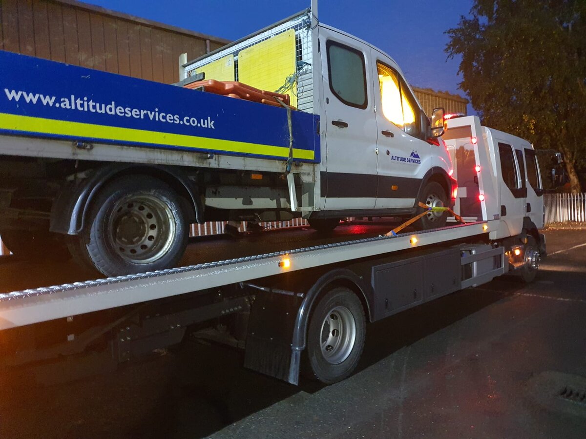 Altitude Services Ford Transit dropside van loaded on the Breakdown Man flatbed at night for commercial van recovery.