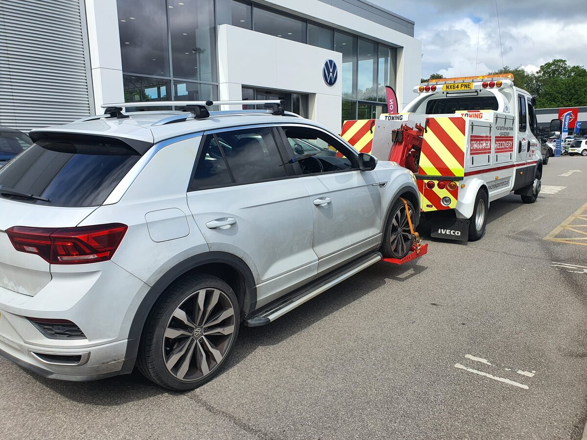 Silver Volkswagen T-Roc loaded onto a Breakdown Man Iveco recovery truck outside a VW dealership for transport back to Atherton.