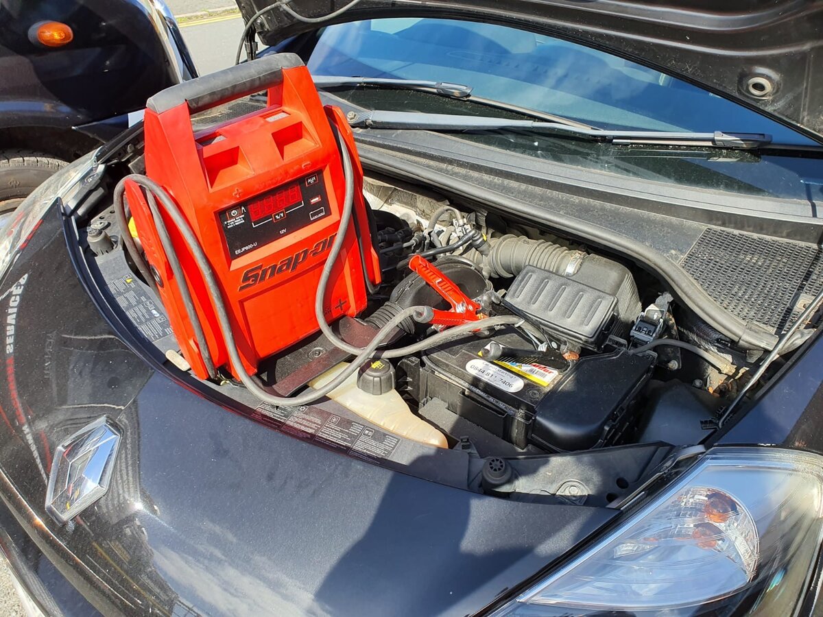 Black Renault sports car with bonnet open and a red Snap-on jump pack ready for a roadside jump start.