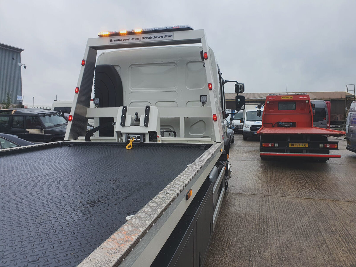 Rear view of the Breakdown Man branded flatbed truck parked at the depot alongside another recovery vehicle.
