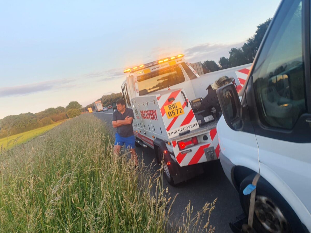 Breakdown Man recovery truck RIG 8572 attending a roadside callout at dusk with a white van behind.