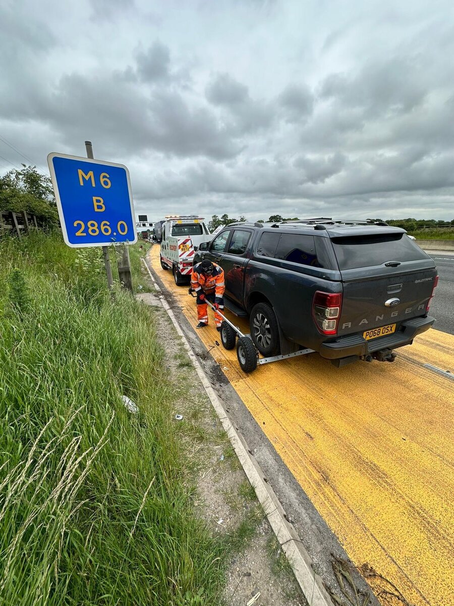 Breakdown Man recovery operator securing a grey Ford Ranger Wildtrak to the recovery truck beside the M6 hard shoulder.