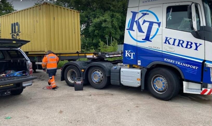 Kirby Transport blue and white Volvo FH 500 HGV tractor unit attended by Breakdown Man at a depot for a roadside jump start.