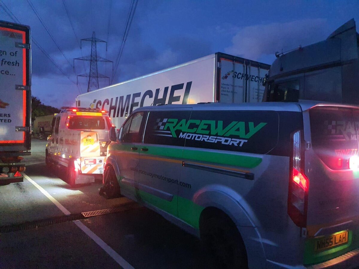 Breakdown Man recovery truck on a dusk motorway shoulder with a Raceway Motorsport Ford Transit van NN55 LAH and articulated lorry alongside.