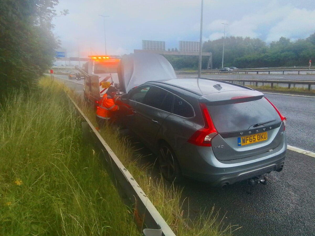 Silver Volvo V60 estate WF65 OKU loaded onto Breakdown Man's recovery truck on a misty motorway hard shoulder.