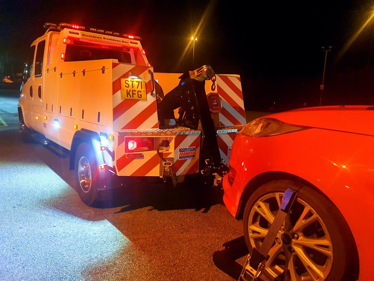Night-time towing of a red car from a car park.