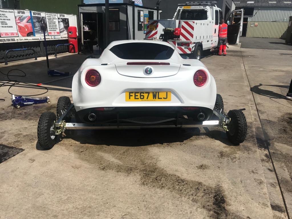 White Alfa Romeo 4C sports car on recovery dollies in front of the Breakdown Man Iveco truck at the yard, ready for safe transport to Preston.