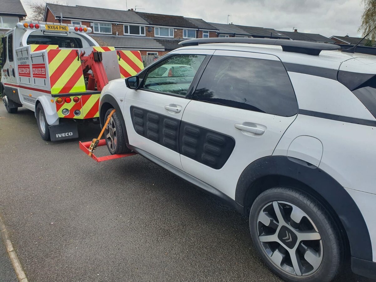Breakdown Man Iveco recovery truck NX64 PNE loaded with a white Citroen C4 Cactus on a residential street