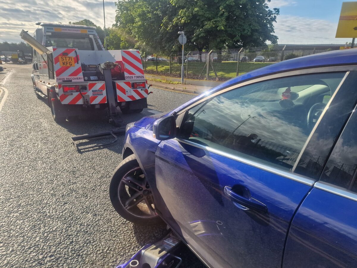 Damaged blue car at the roadside next to Breakdown Man recovery truck ST71 KFG ready to load.