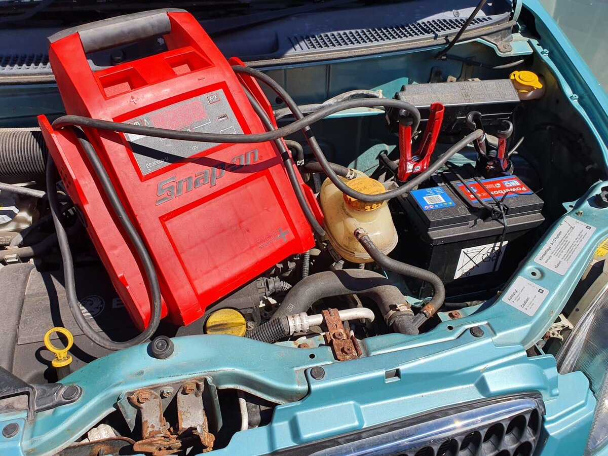 Snap-on red jump pack clamped to a car battery in the engine bay during a Breakdown Man flat-battery callout.