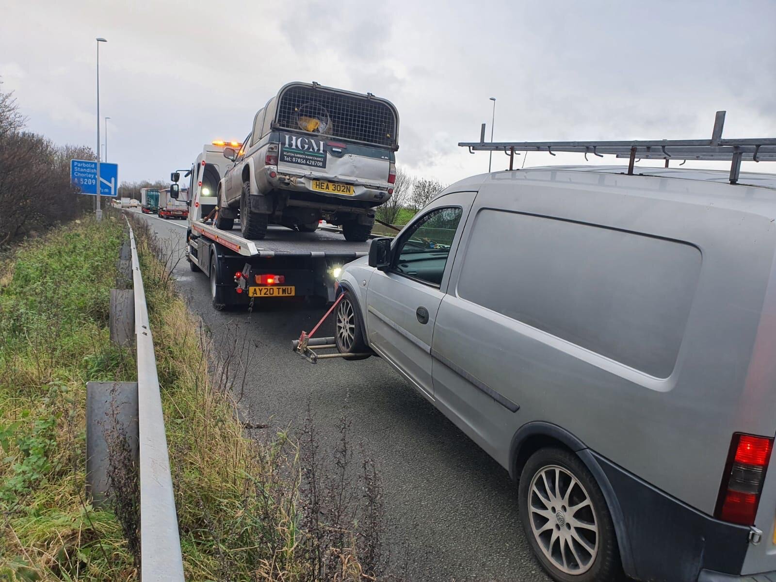 A Land Rover Defender loaded onto a recovery truck on the motorway hard shoulder.