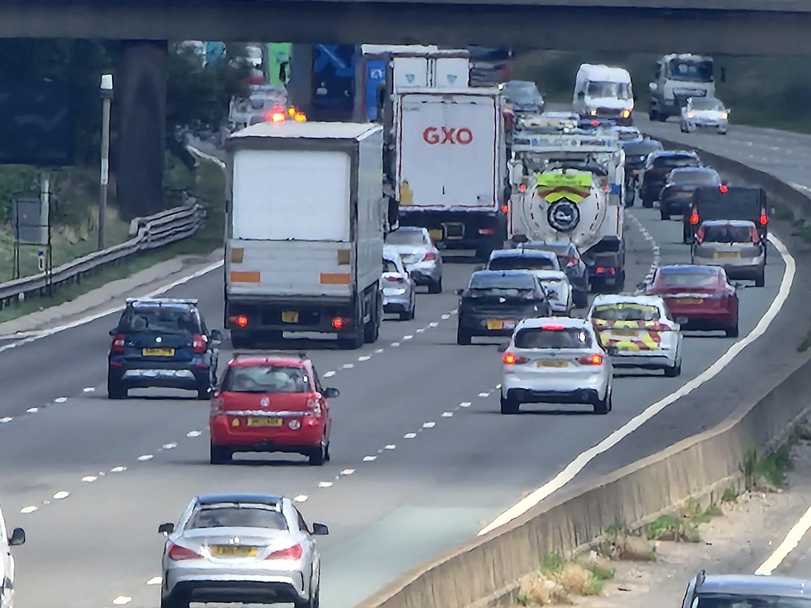 Three-lane motorway traffic flowing under a bridge — the corridor Breakdown Man covers 24/7.