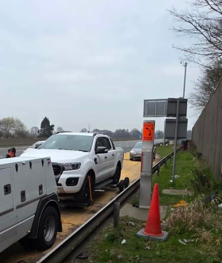Recovery truck attending a motorway breakdown near SOS phone.