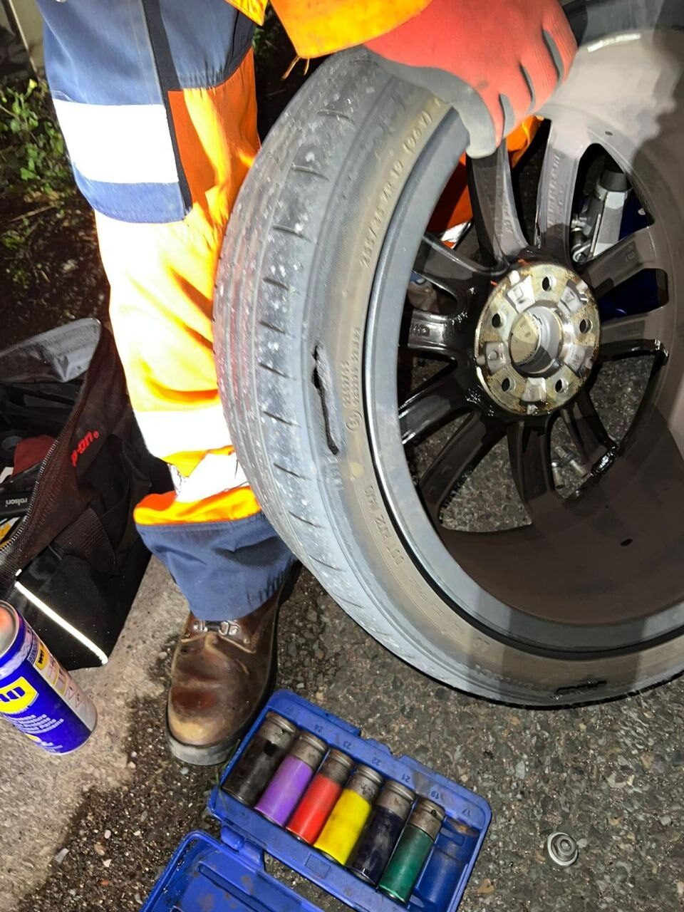 Breakdown Man fitting a tyre to a car's alloy wheel at the roadside.