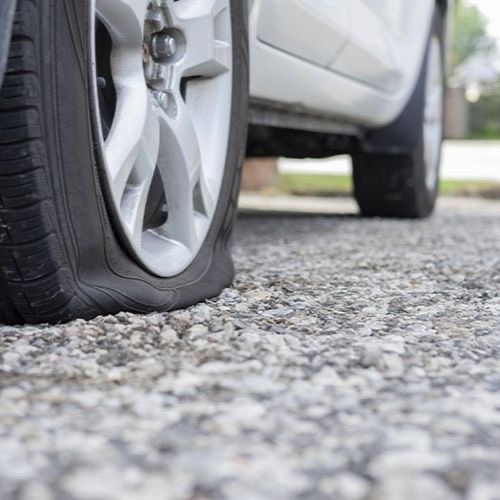 A deflated car tyre at the kerb.