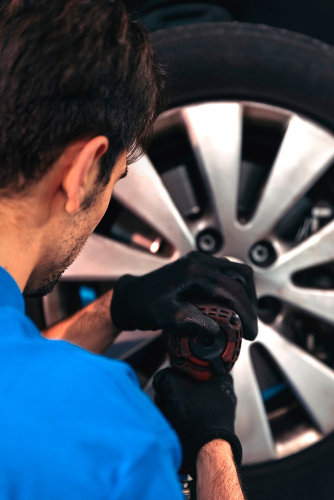 A mechanic using an impact gun to fit an alloy wheel