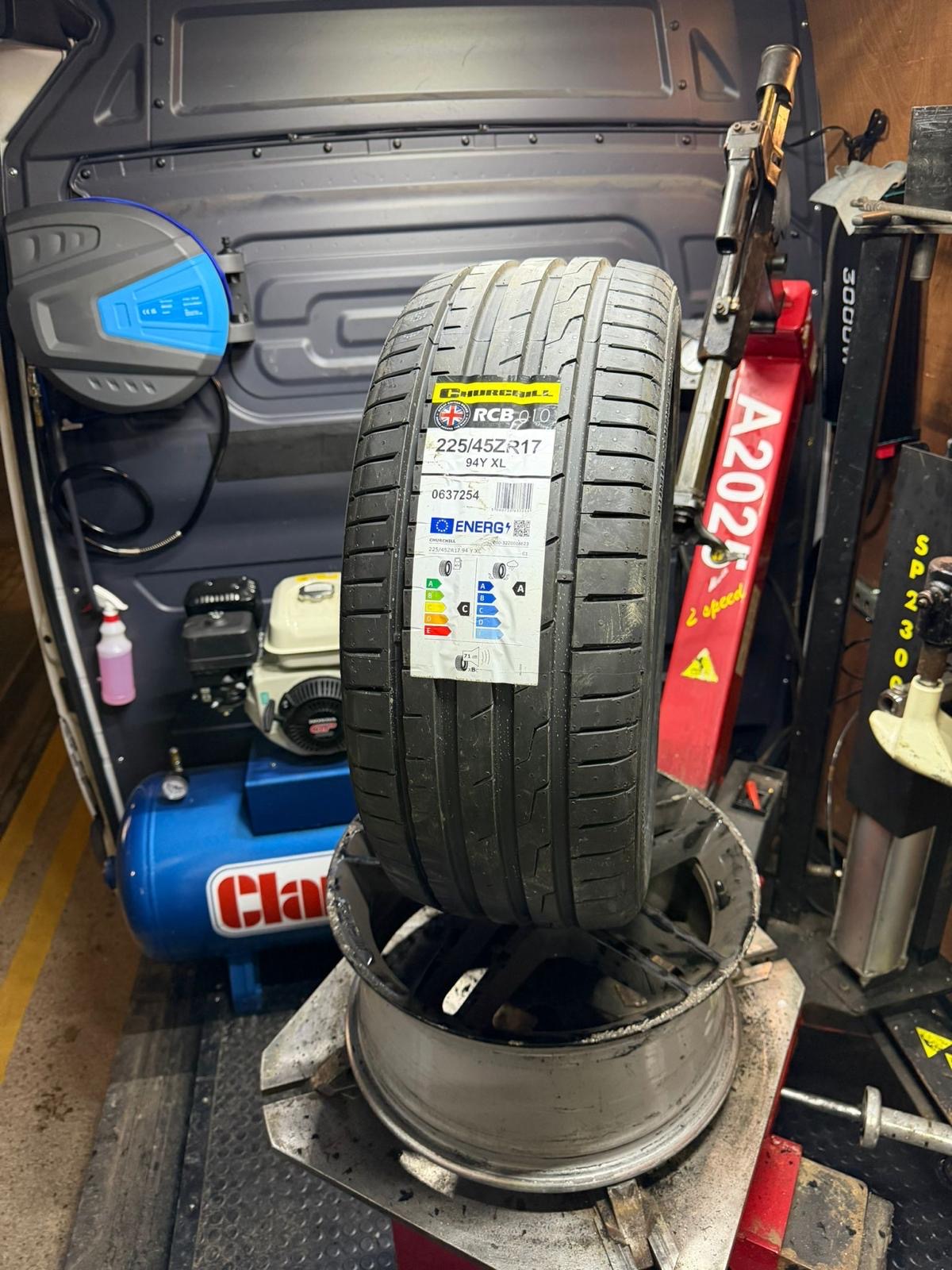 A new tyre on an alloy rim in a workshop bay.